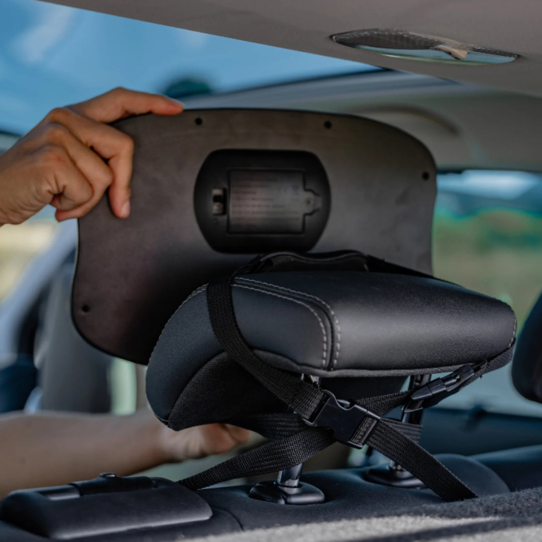 Adult installing the EziMoov LED baby car seat mirror onto a rear headrest, showing the adjustable strap system and secure attachment for clear rear-facing infant monitoring while driving.