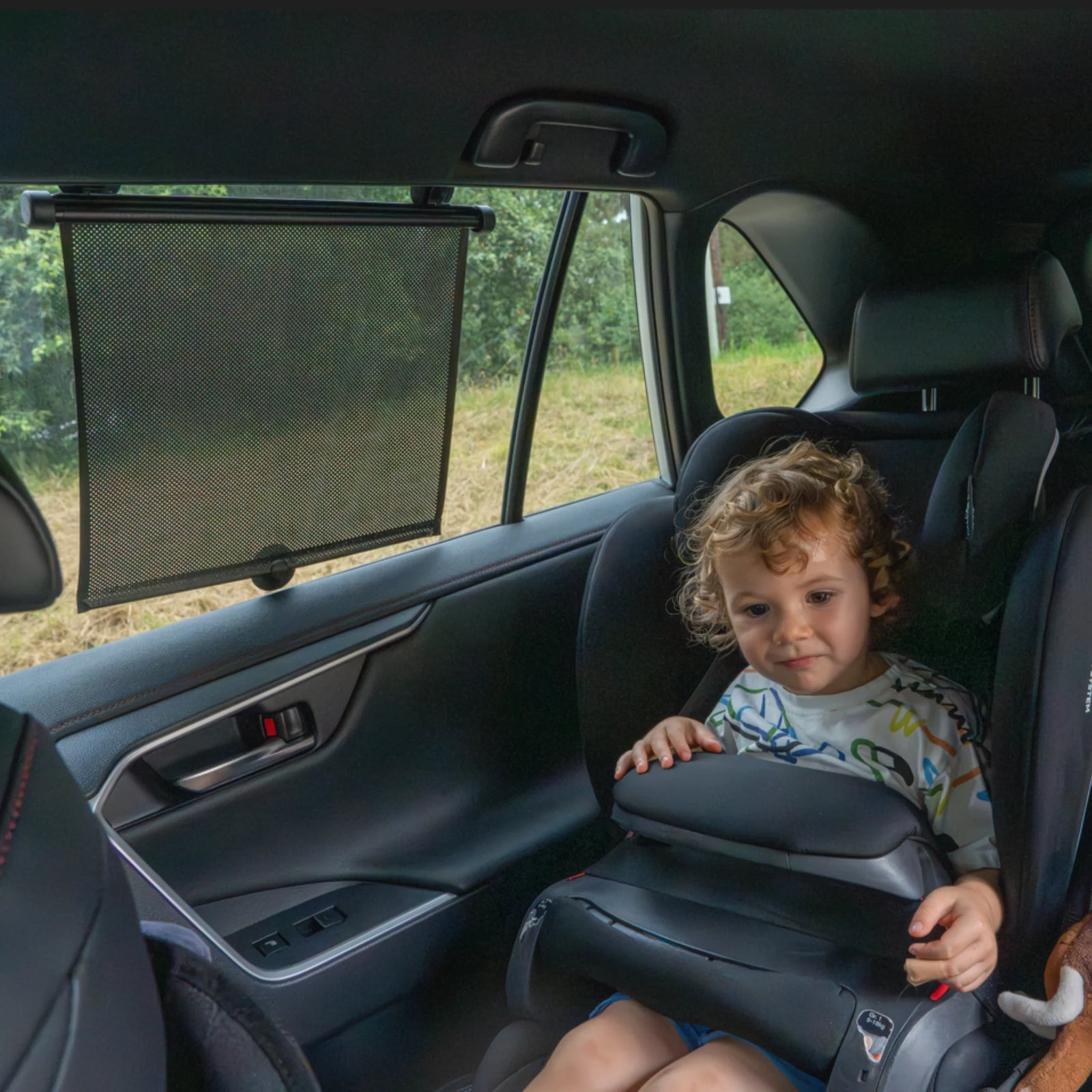 This image shows the Ezimoov Retractable Car Sun Shade installed in the back of a car.
