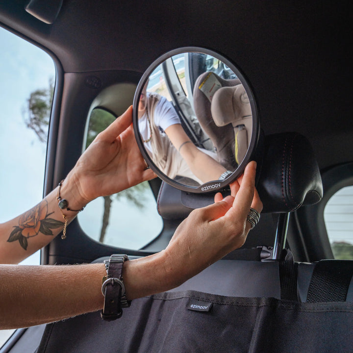 A parent is adjusting the mirror for the perfect angle of the car seat.