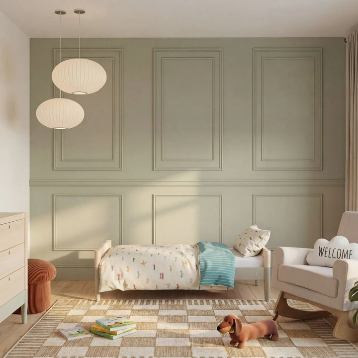 Gaia Baby Eos convertible cot transformed into toddler bed in natural desert sage finish in a modern nursery with soft lighting and neutral decor