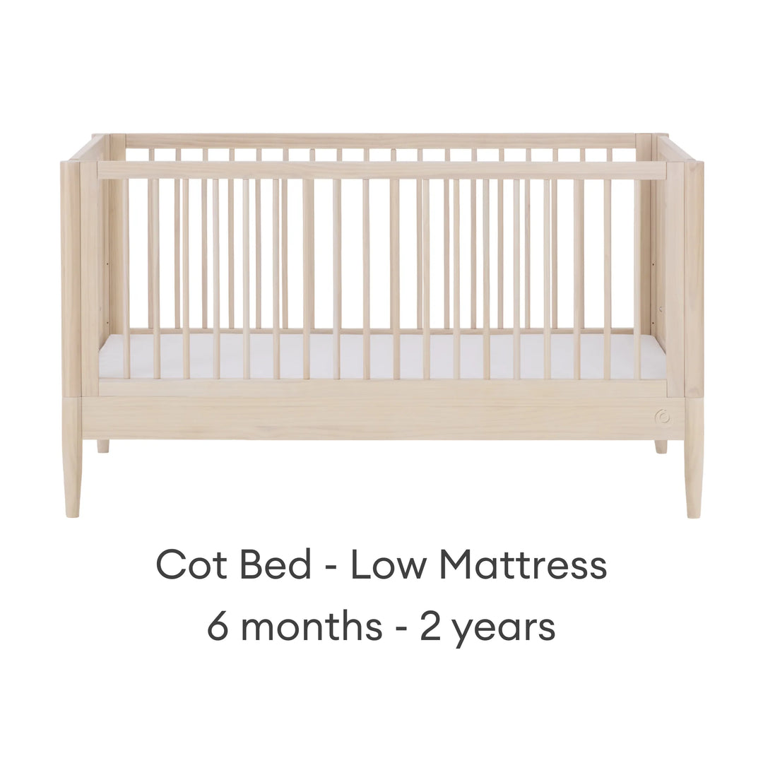 Gaia Baby Eos convertible cot in all-natural wood finish with mattress in low position for 6 months to 2 years on a white background.
