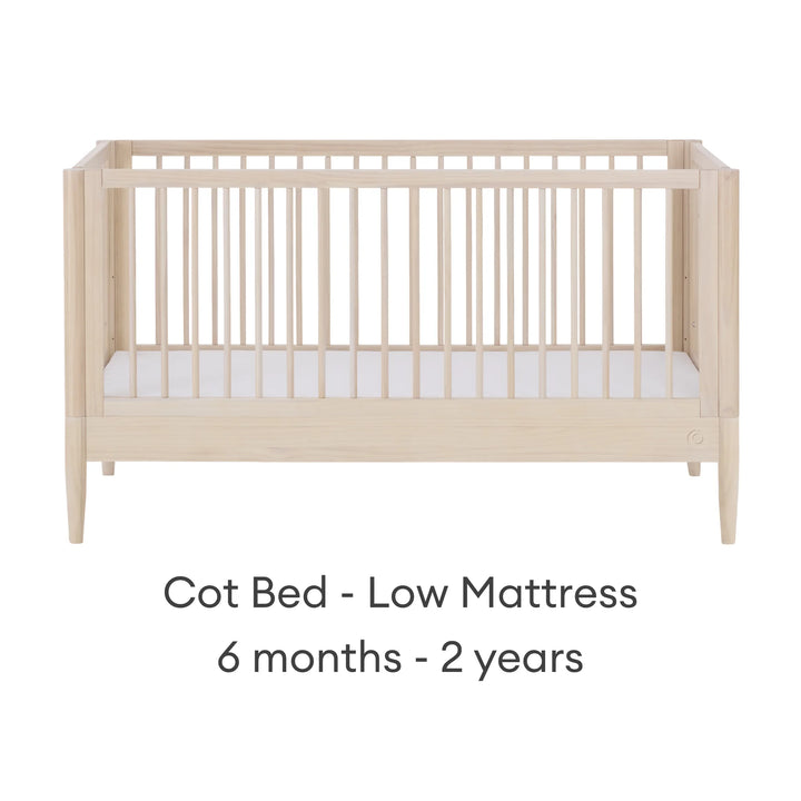 Gaia Baby Eos convertible cot in all-natural wood finish with mattress in low position for 6 months to 2 years on a white background.