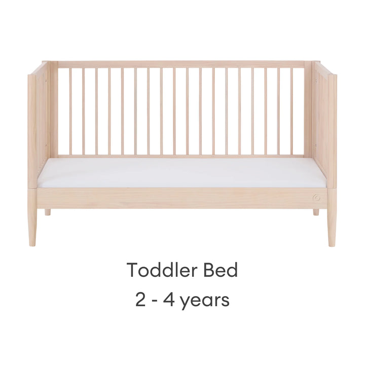 Gaia Baby Eos convertible cot transformed into toddler bed for ages 2–4 years in all-natural wood finish on a white background.