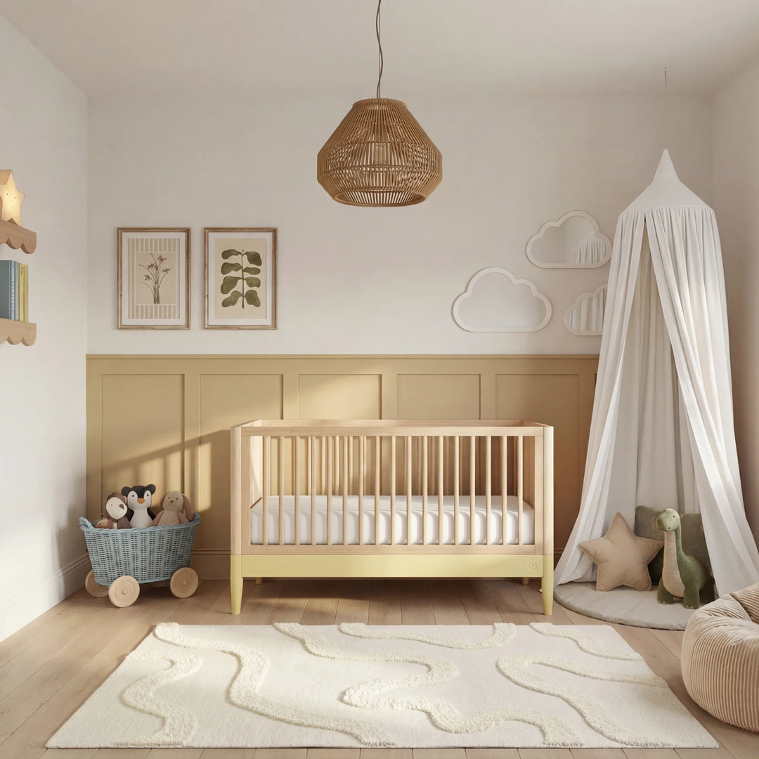 Gaia Baby Eos convertible cot in natural wood and primrose yellow in a warm neutral nursery with canopy, wooden floor and soft decor.