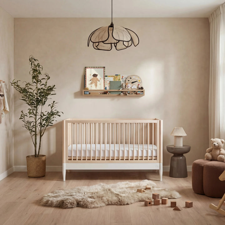 Gaia Baby Eos convertible cot bed natural wood and white in warm neutral nursery with teddy bear rug wooden toys and modern baby crib setup