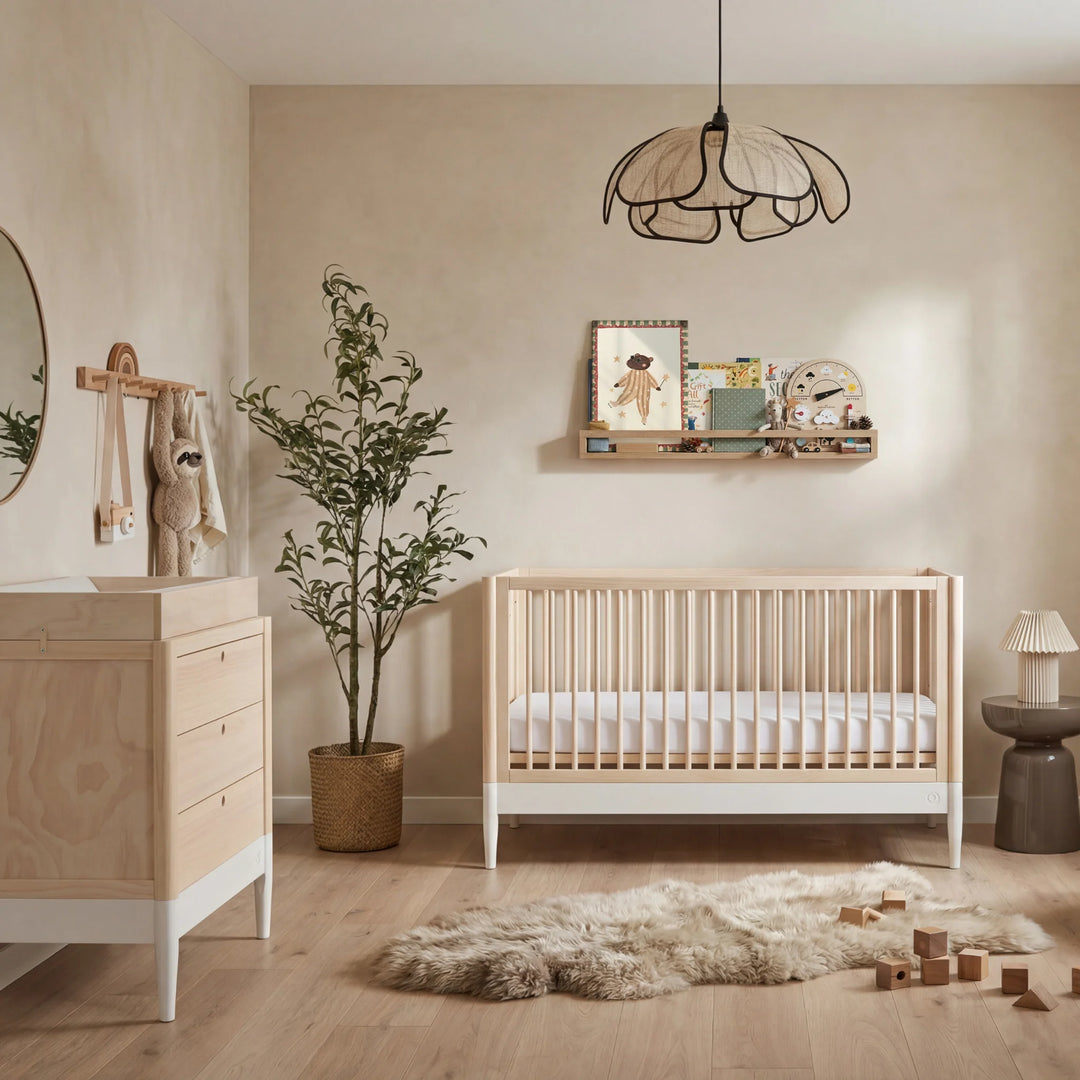 Gaia Baby Eos convertible cot in natural wood finish in a modern nursery with wooden crib, dresser, and neutral décor