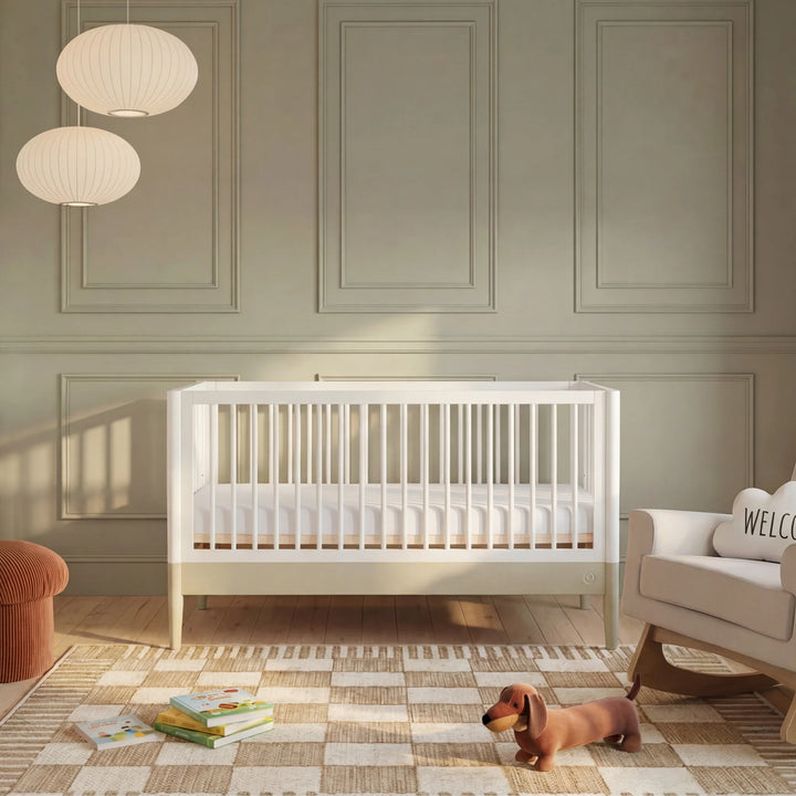 Gaia Baby Eos convertible cot bed white and cashmere in modern nursery room with wooden floor books and soft lighting baby crib setup
