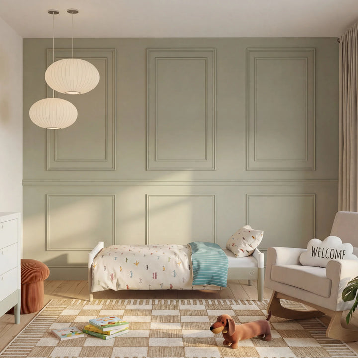 Gaia Baby Eos convertible cot bed transformed into toddler bed in modern nursery room with green panelled walls and soft furnishings white and cashmere