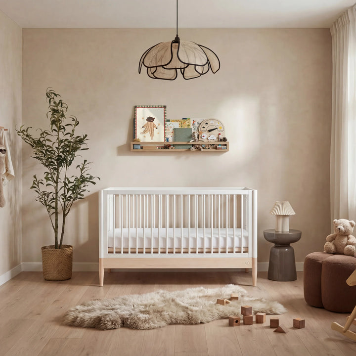 Gaia Baby Eos convertible cot bed white and natural wood in warm neutral nursery with wooden floor soft textures and baby crib setup