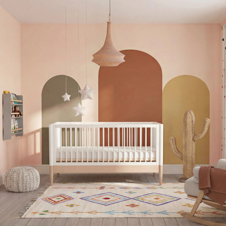 Gaia Baby Eos convertible cot in white and powder blush in a styled nursery with colourful wall arches, rug, and decorative accessories