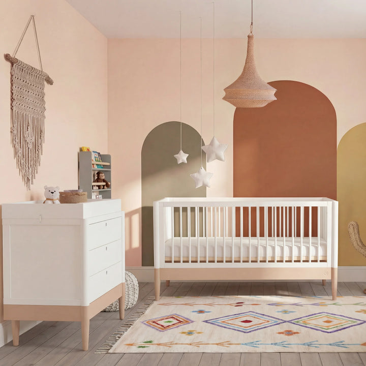 Gaia Baby Eos cot bed and dresser set in white and natural wood styled in powder blush nursery with colourful rug