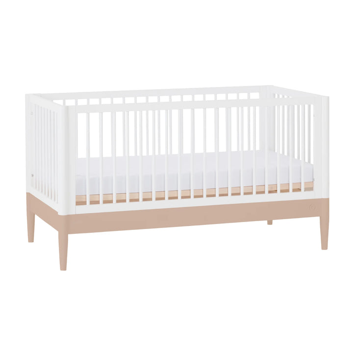 Gaia Baby Eos convertible cot in white and powder blush shown at an angle with mattress on a white background