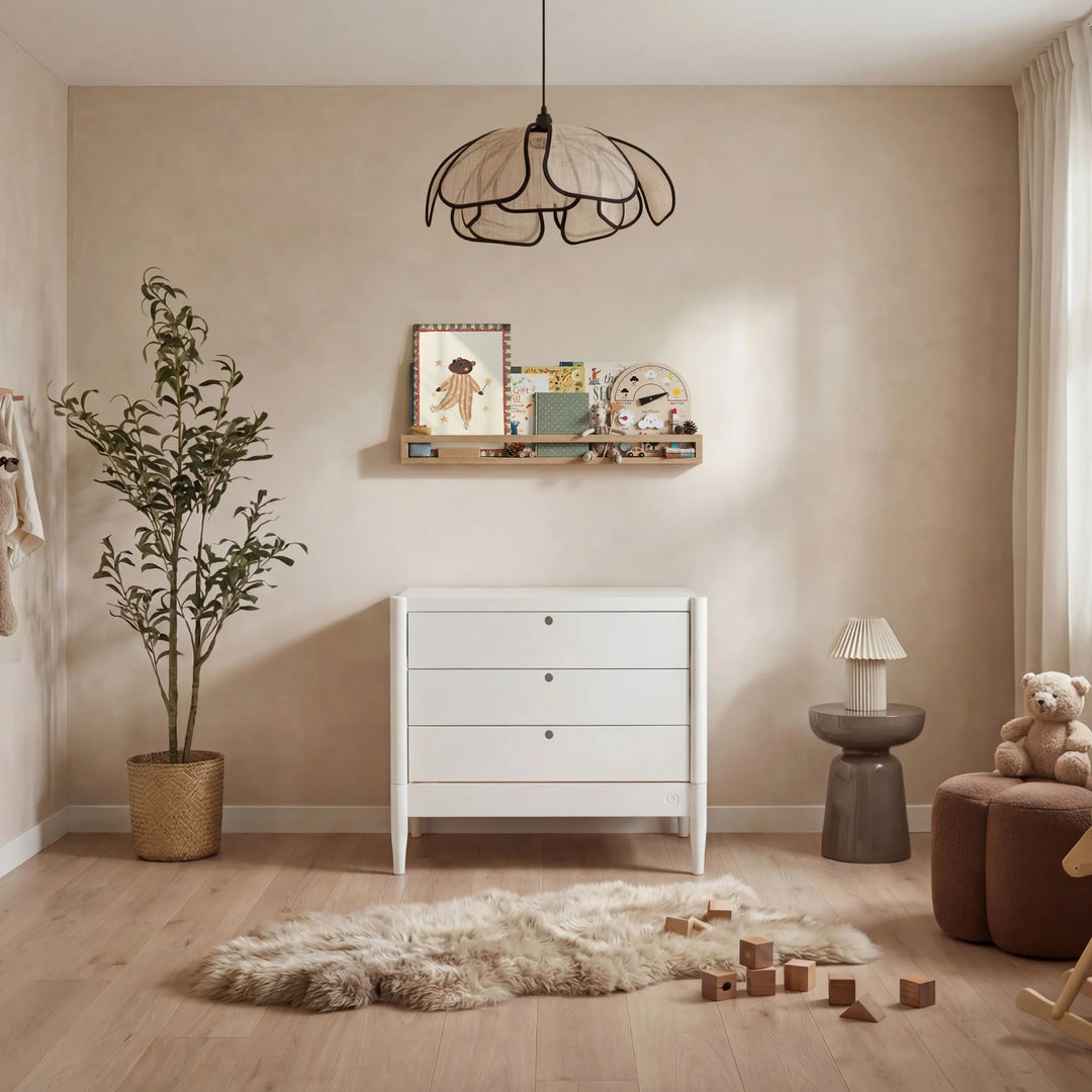 Gaia Baby Eos white dresser in a modern nursery room with wooden floor, soft lighting and decor