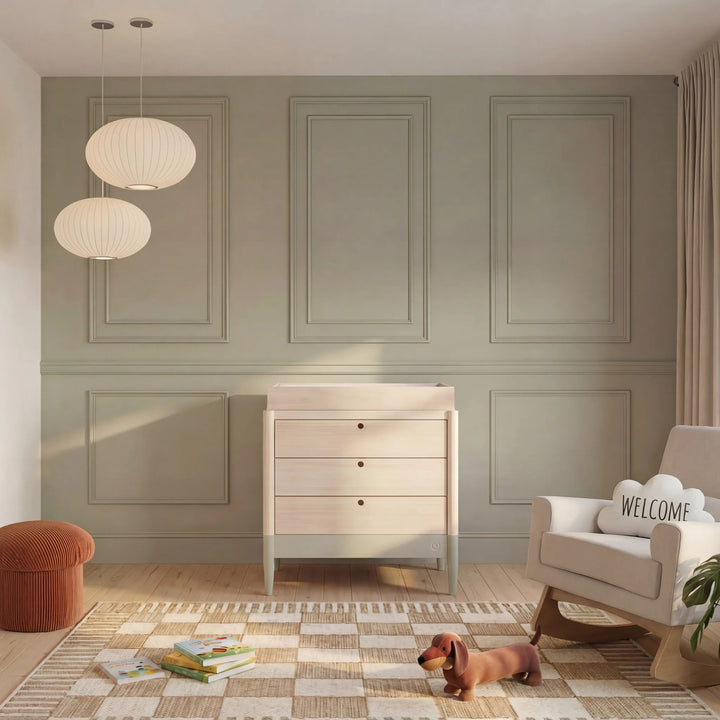 Gaia Baby Eos dresser in natural wood and desert sage with changing top in a modern nursery with soft neutral decor