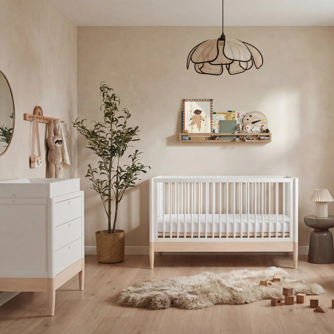 Gaia Baby Eos dresser in white and natural wood in a nursery with cot, plant, and shelf