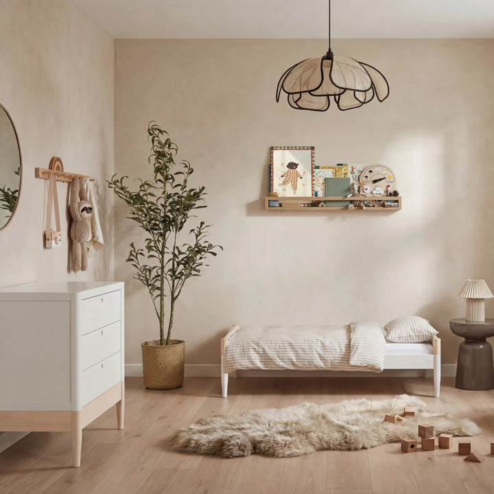 Gaia Baby Eos dresser in white and natural wood in a nursery with toddler bed, plant, and shelf