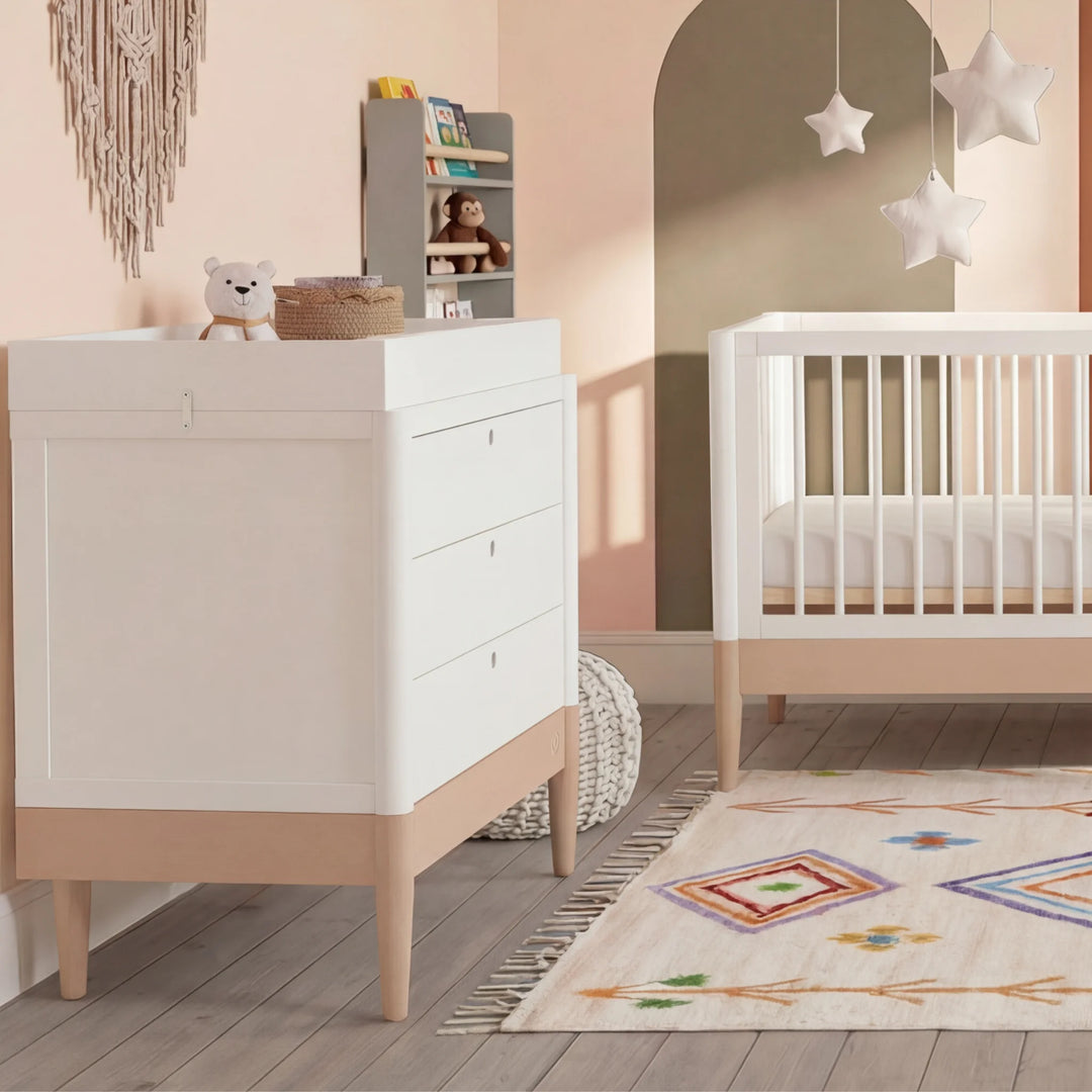 Gaia Baby Eos dresser in white and powder blush with changing top in a nursery with cot and rug