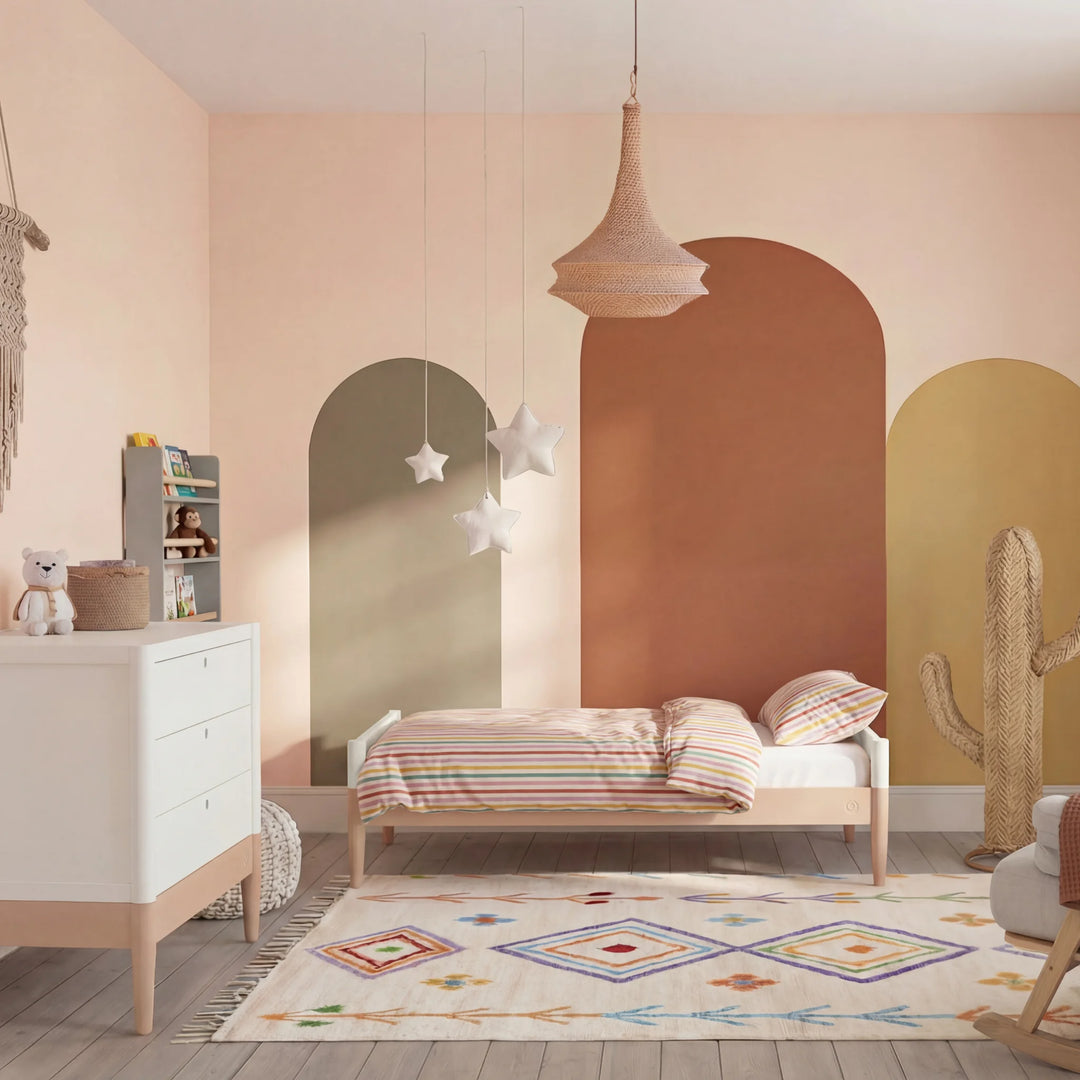 Gaia Baby Eos dresser in white and powder blush in a nursery with toddler bed, rug, and decor