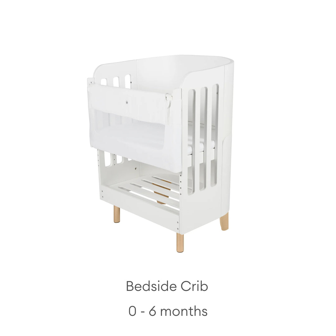 Gaia Baby Serena bedside crib add-on in white with natural wooden legs on a white background