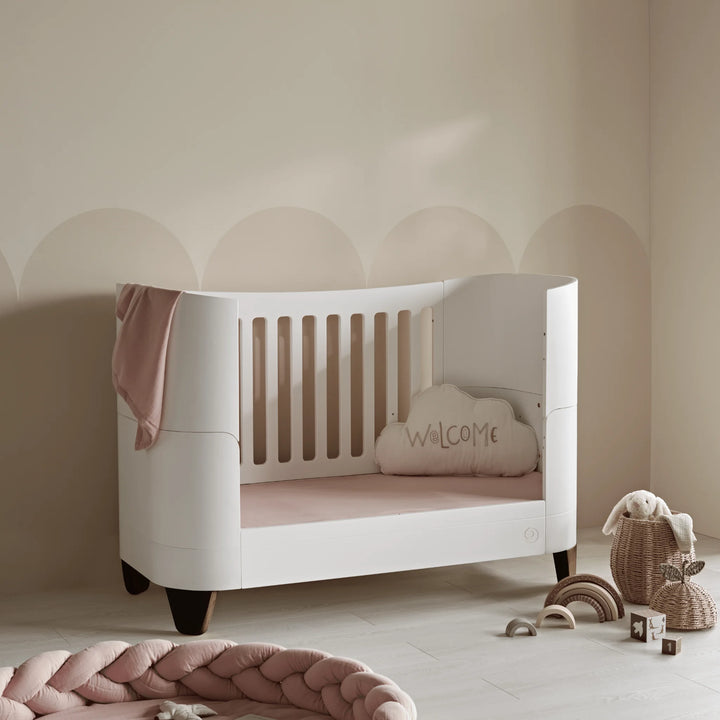Serena convertible cot bed with walnut legs in toddler bed mode in a pink themed nursery.