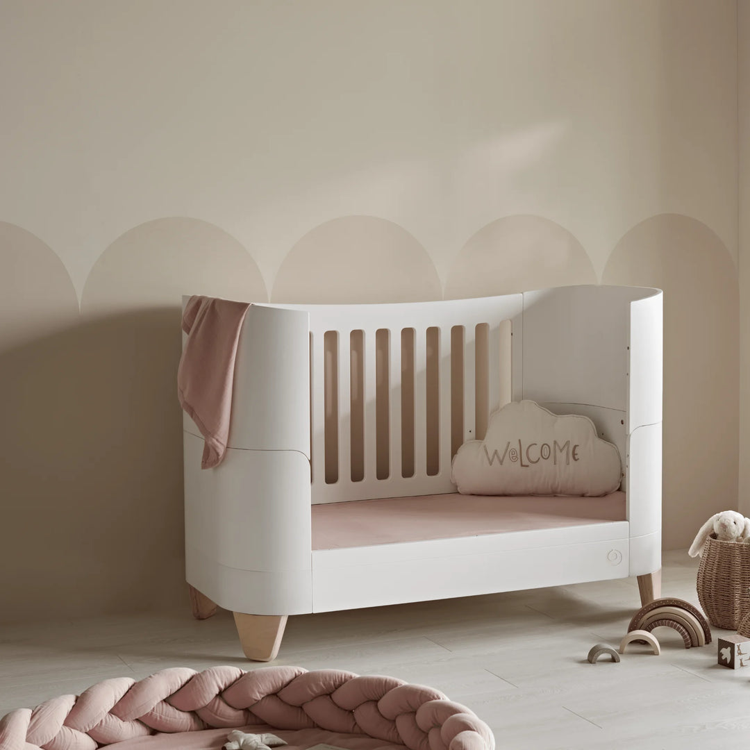 Serena real wood cot bed in toddler bed mode in neutral nursery with pink pops of colour.