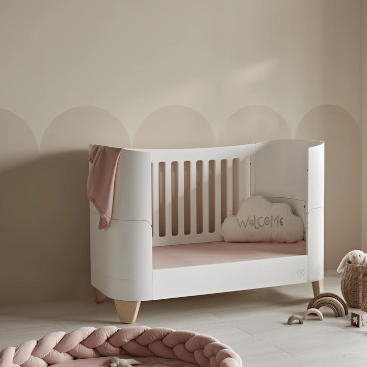 Serena real wood cot bed in toddler bed mode in neutral nursery with pink pops of colour.