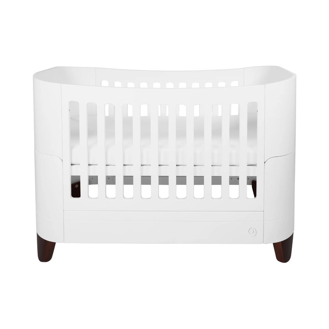 Serena solid wood convertible cot bed with walnut legs on a white background.