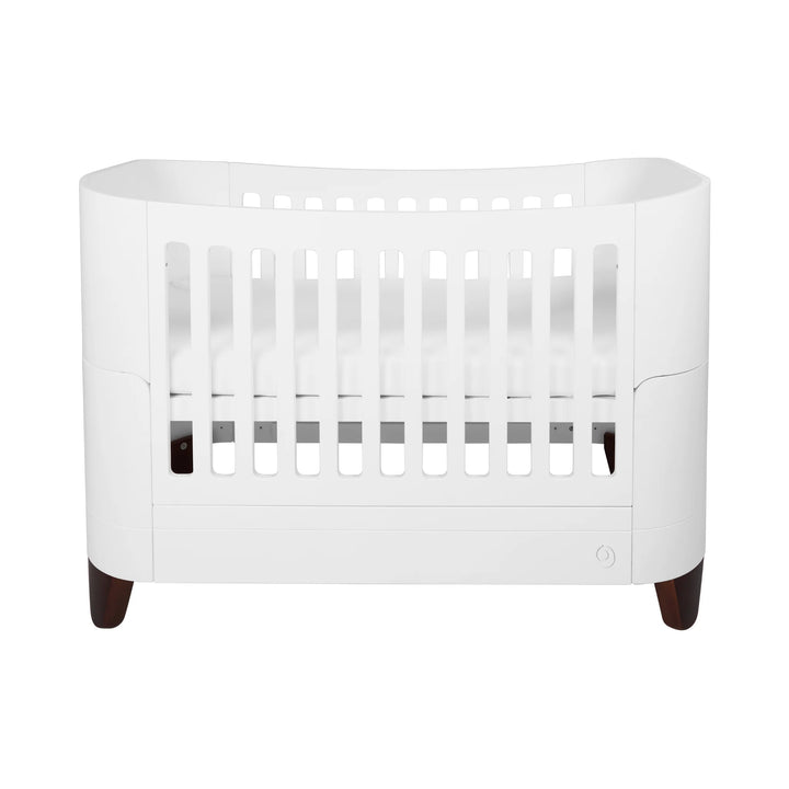 Serena solid wood convertible cot bed with walnut legs on a white background.