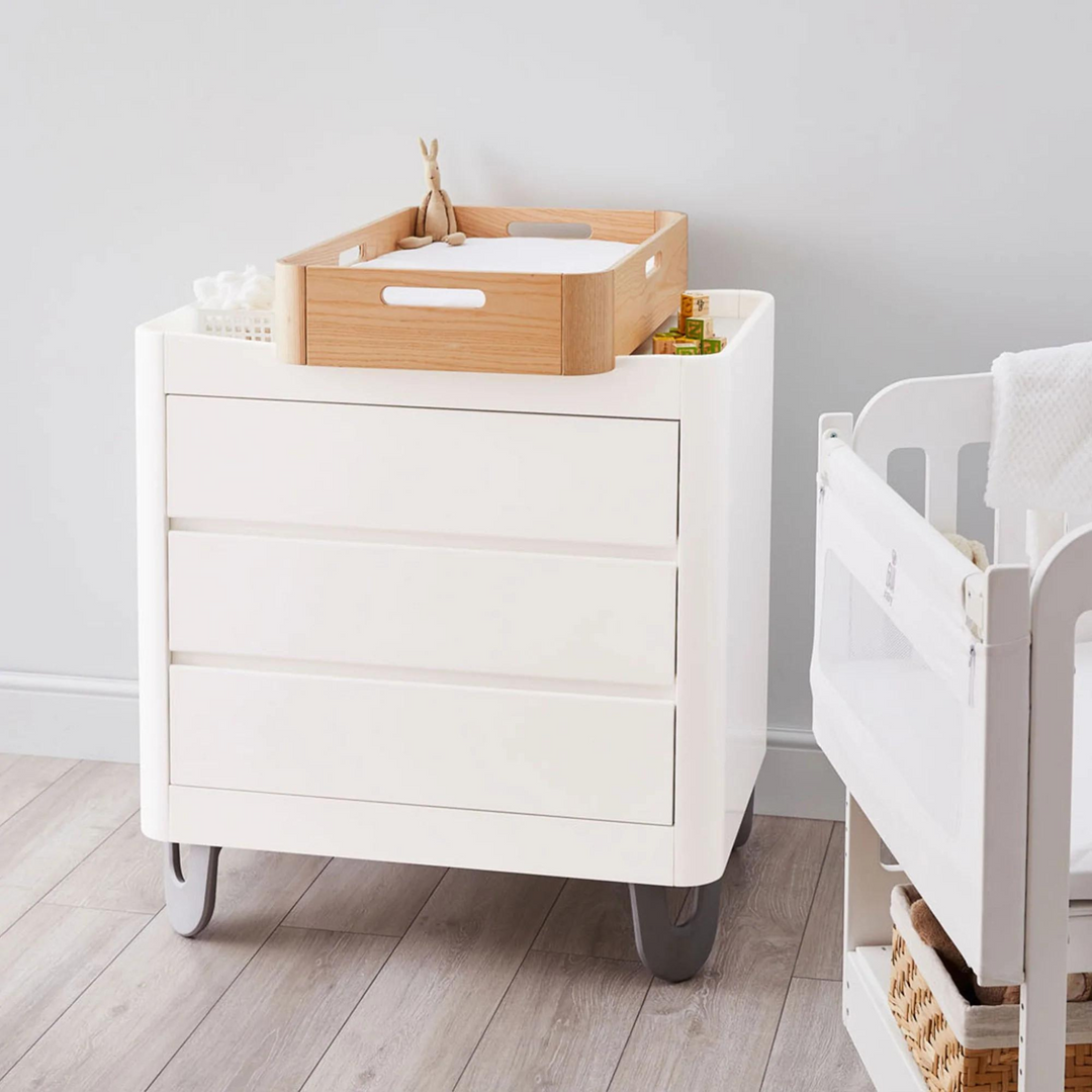 This image shows the Serena Dresser in a nursery with the Hera Changing Station in Natural on top of the dresser.