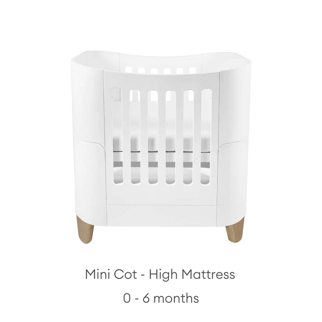 Real wood baby cot with text: mini cot - high mattress: 0 - 6 months.