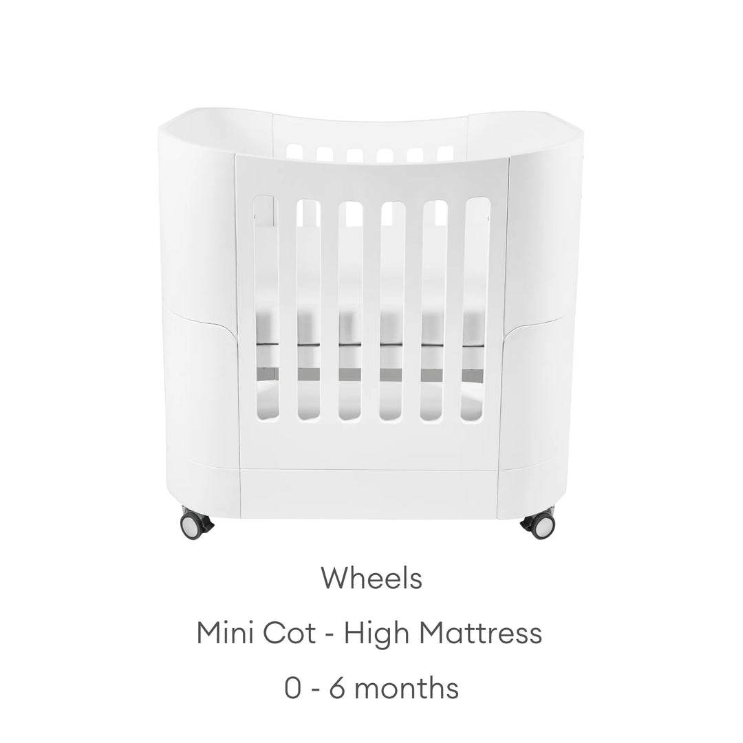 Real wood baby cot with text: mini cot - high mattress with wheels: 0 - 6 months.