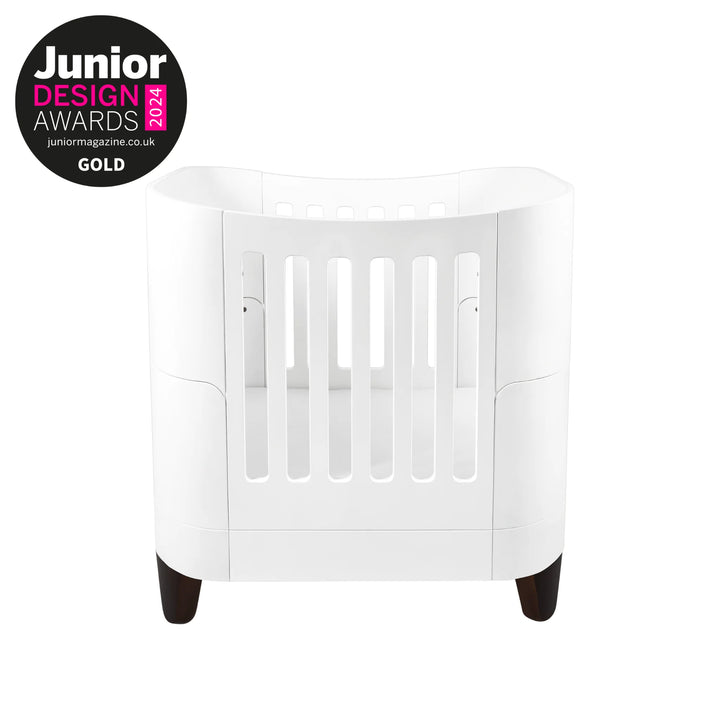 Serena Small Cot Bed with Walnut Legs and Gold Junior Design Awards 2024 logo.