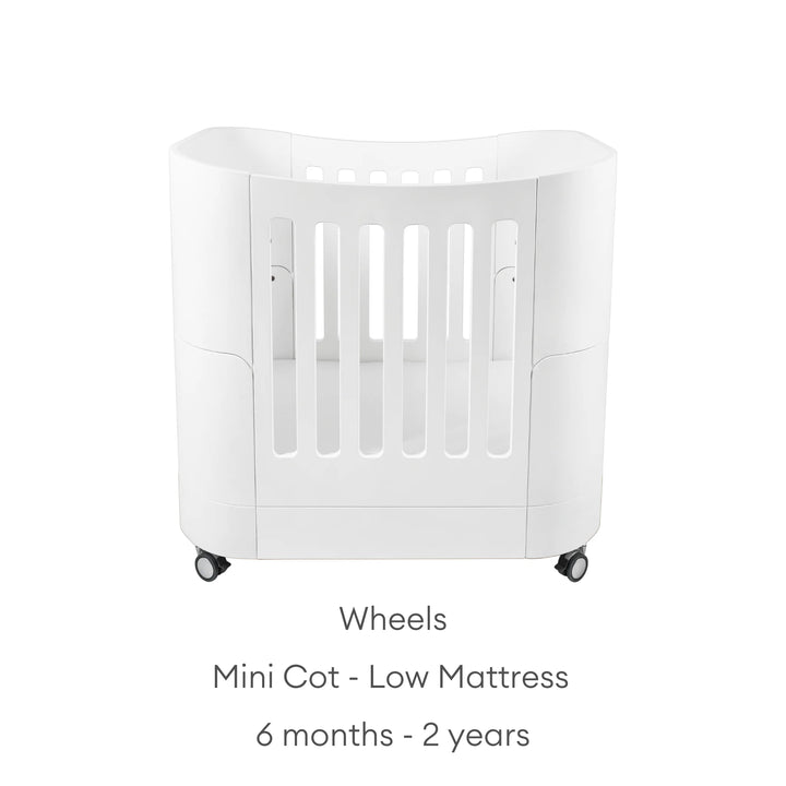 Real wood baby cot with text: mini cot - low mattress with wheels: 6 months - 2 years.