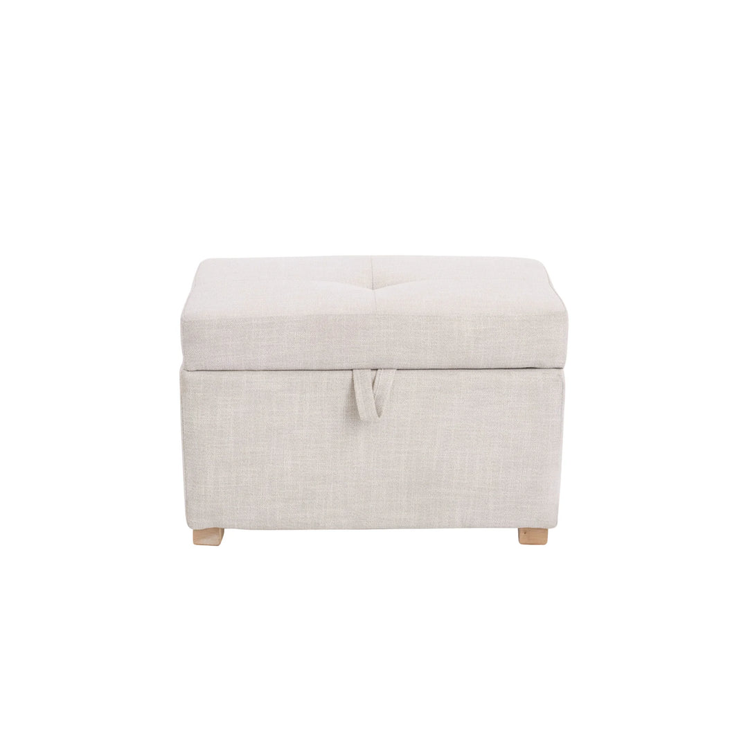 The Gaia Baby Serena Footstool in oat fabric shown from the front on a white background, featuring a soft upholstered storage ottoman with a pull-tab lid detail and light wooden feet.