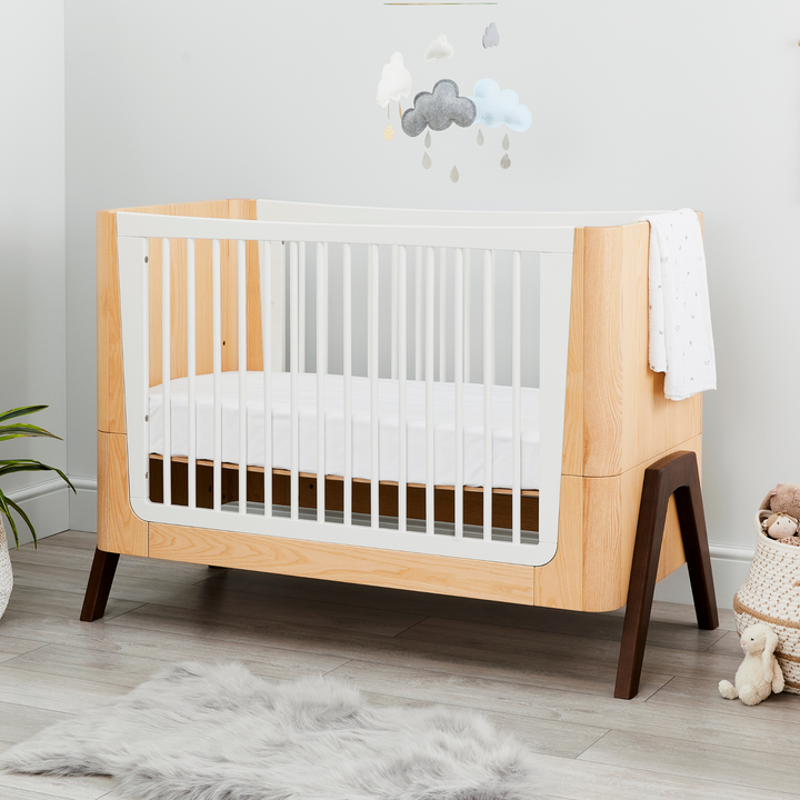 Lifestyle image of Hera Cot Bed in Natural Ash and Walnut in the mid mattress level