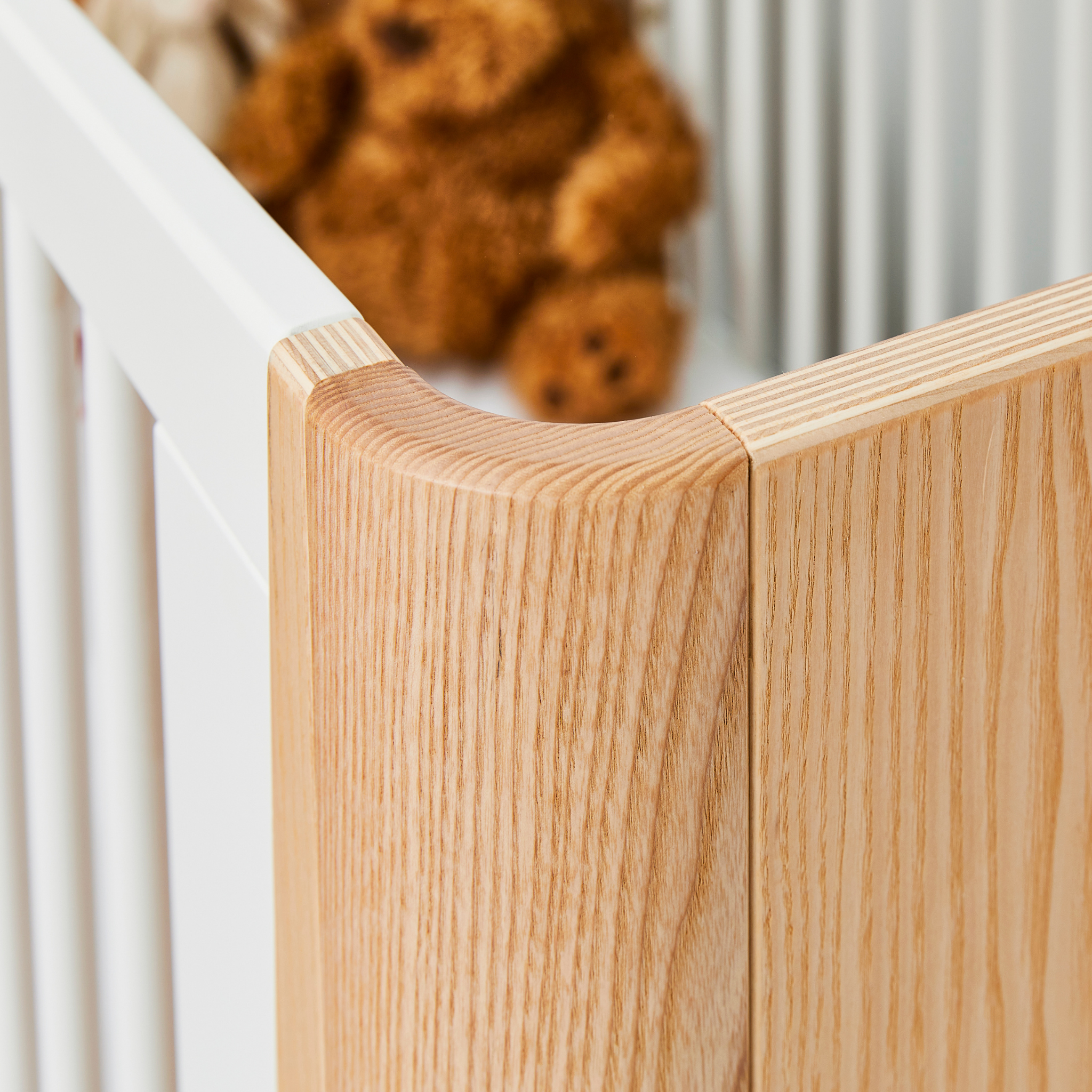 Close up detail of the wood gain on the Hera Cot Bed in Natural Ash and Walnut