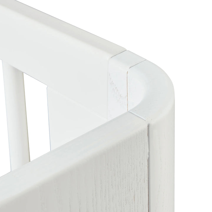 “Close-up of Gaia Baby Hera cot bed in Scandi White showing smooth rounded top rail, precision joinery and white slatted side — modern Scandinavian premium nursery furniture craftsmanship