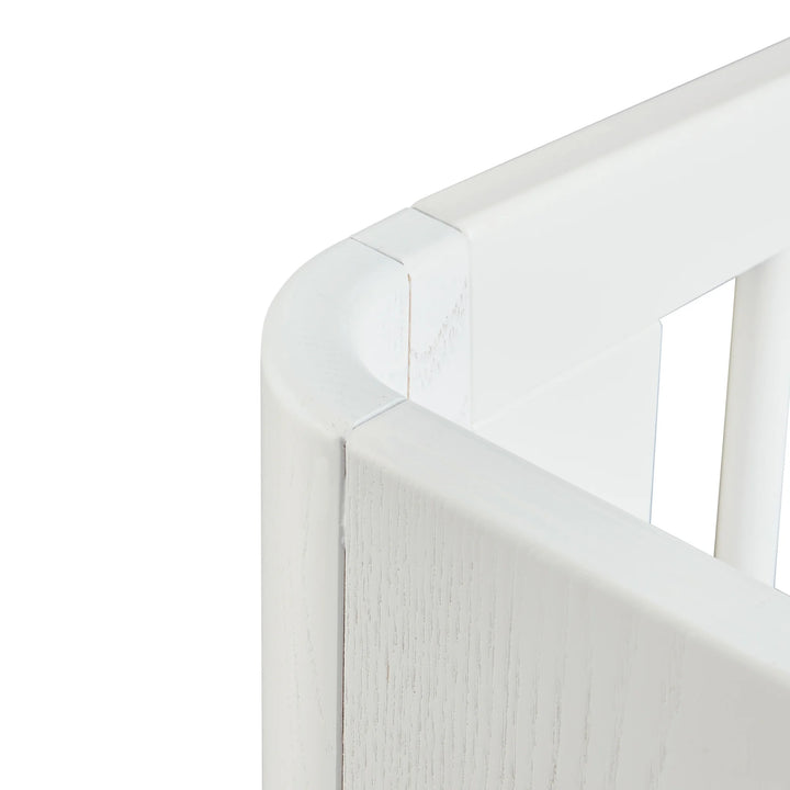 “Close-up of Gaia Baby Hera cot bed in Scandi White showing smooth rounded top rail, precision joinery and white slatted side — modern Scandinavian premium nursery furniture craftsmanship