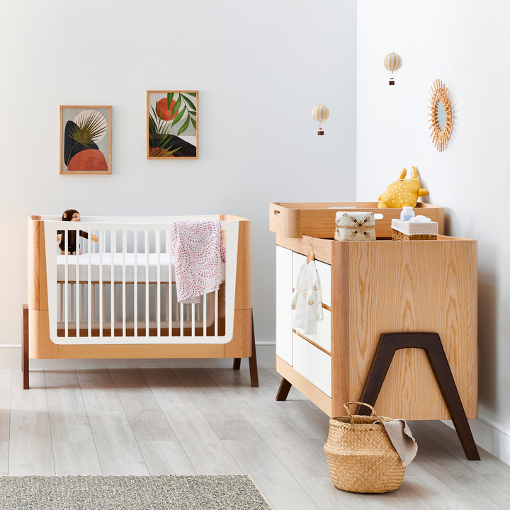 lifestyle image of Hera Cot Bed and Hera Dresser in Natural Ash and Walnut
