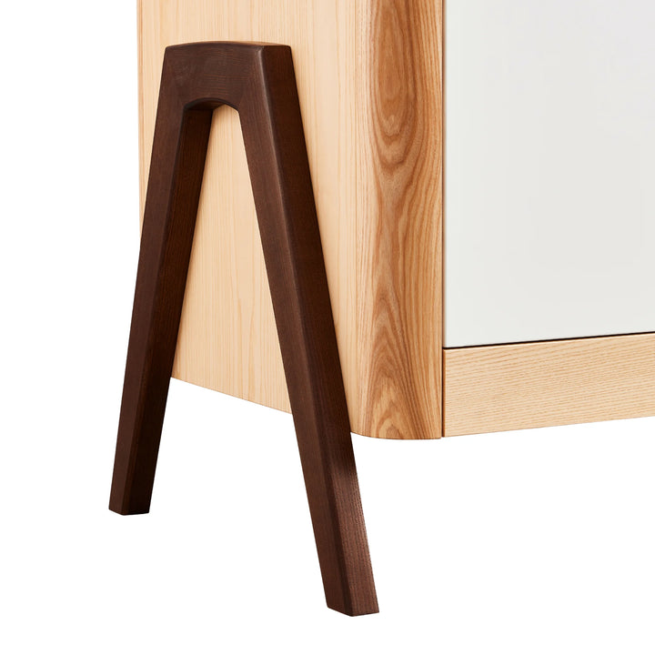 Close-up of Gaia Baby Hera dresser ash and walnut A-frame leg, highlighting solid walnut construction, natural wood grain, and premium Scandinavian nursery furniture craftsmanship.