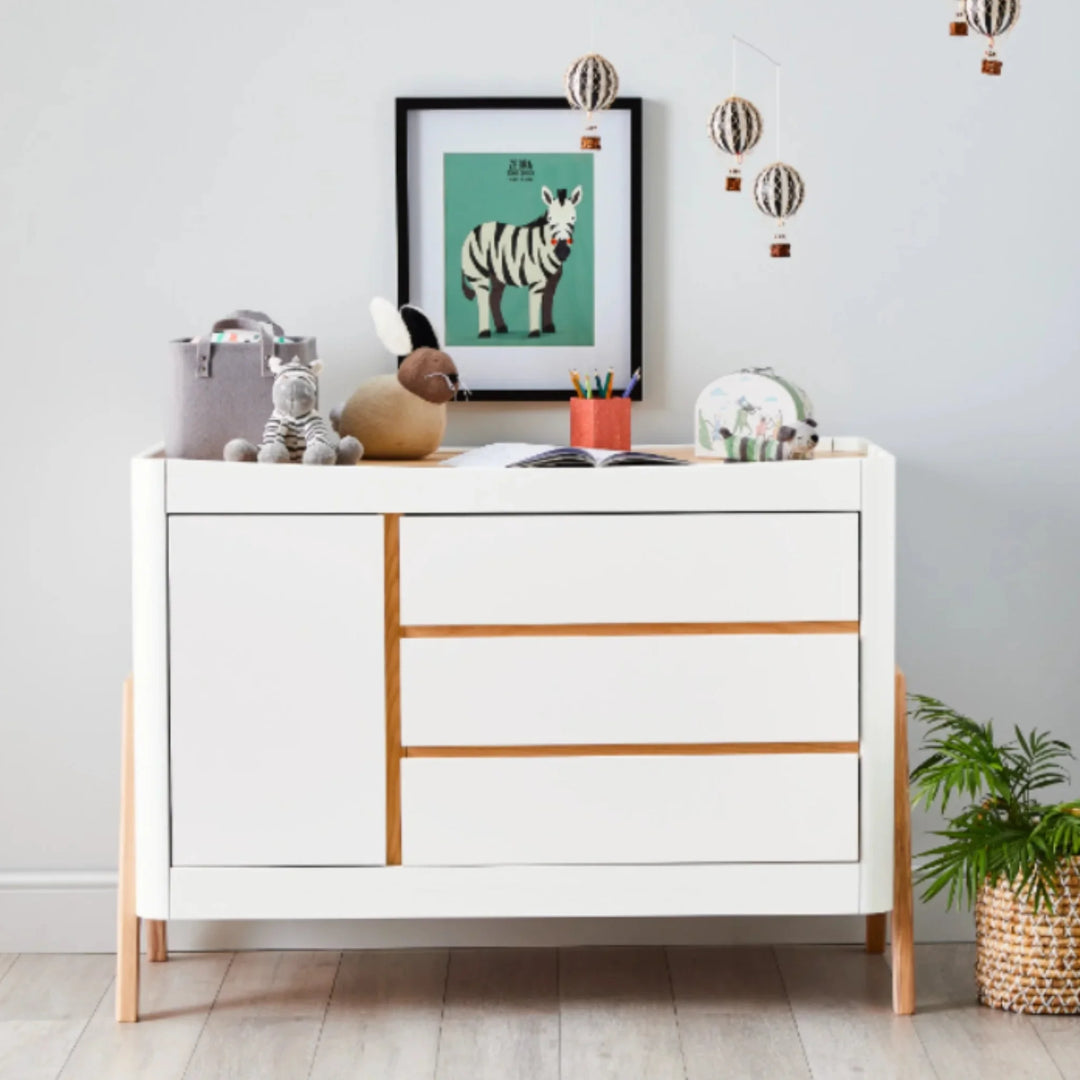 “Gaia Baby Hera dresser in Scandi white and natural wood featured in a modern nursery, styled with toys, décor and wall art, showcasing minimalist Scandinavian design and three-drawer storage.”
