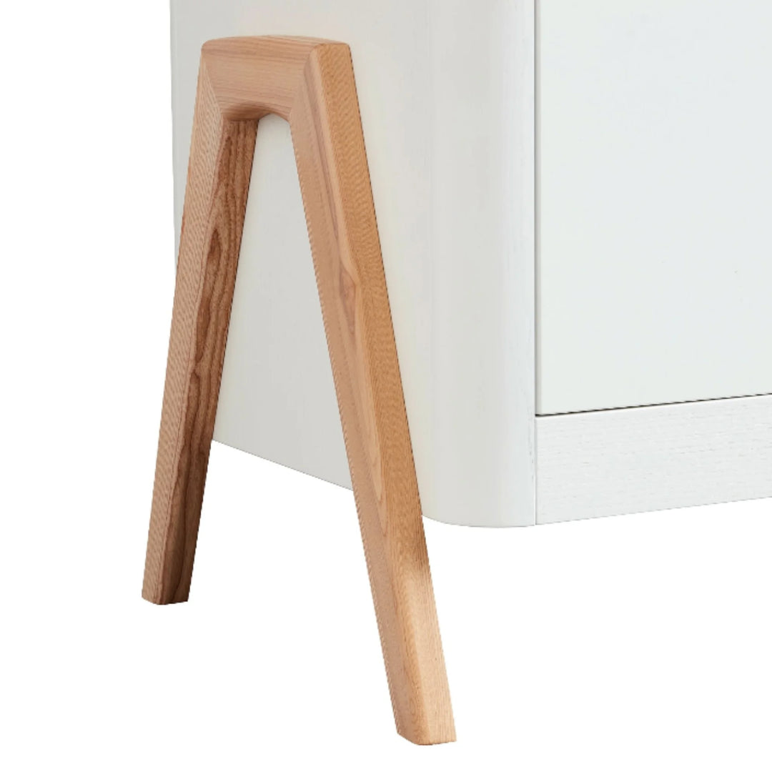 Close-up of the Gaia Baby Hera dresser in Scandi white and natural wood, highlighting the solid ash A-frame leg design and smooth curved edge detailing.
