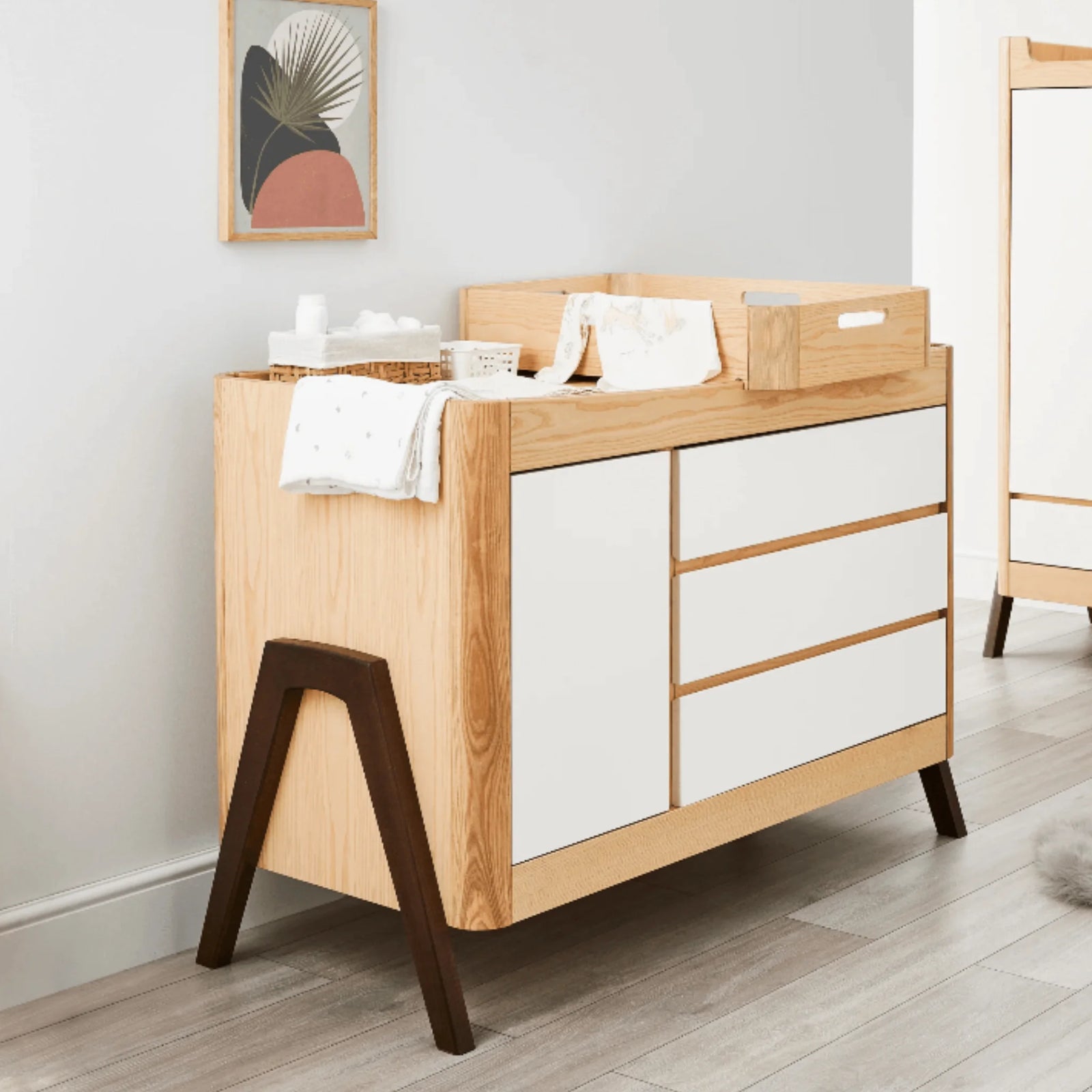 Gaia Baby Hera dresser in Scandi white with natural ash and walnut accents, shown in a modern nursery setup with changing tray, baby essentials and Scandinavian décor