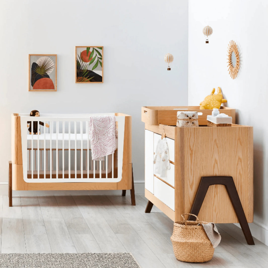 Modern nursery featuring the Gaia Baby Hera dresser and crib in Scandi white and natural wood, styled with wall art, woven baskets and baby essentials to showcase minimalist Scandinavian design