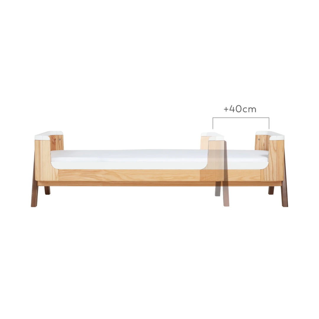 Gaia Baby Hera junior bed extension in natural ash and walnut showing +40cm extended length dimension, illustrating how the toddler bed grows with your child.