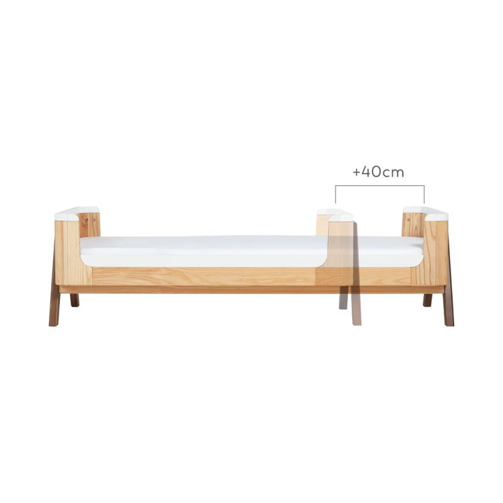 Gaia Baby Hera junior bed extension in natural ash and walnut showing +40cm extended length dimension, illustrating how the toddler bed grows with your child.