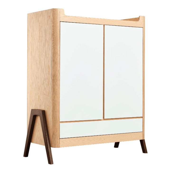 “Gaia Baby Hera wardrobe in Natural Ash and Walnut, modern Scandinavian nursery storage unit with two doors, white panels and contrasting walnut legs.”