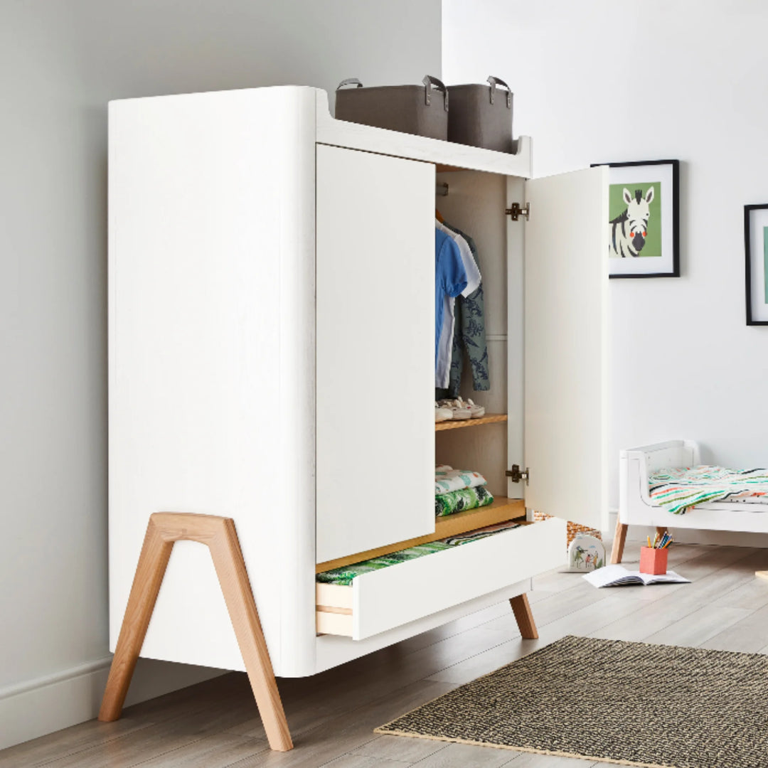 Gaia Baby Hera wardrobe in Scandi white and natural wood shown in a modern nursery, doors open to reveal hanging and shelf storage with bottom drawer extended