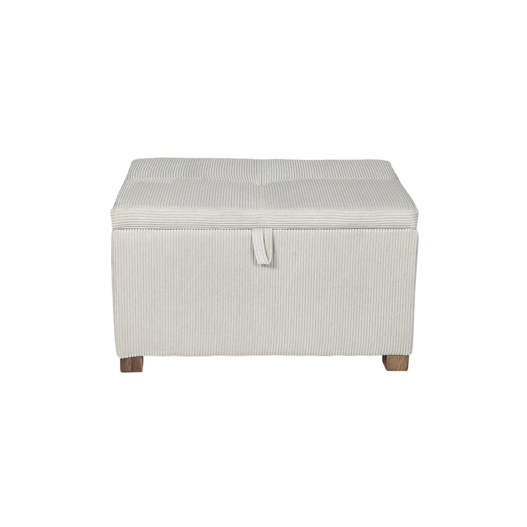 The Gaia Baby Serena Footstool in ecru corduroy fabric shown from the front on a white background, featuring a soft upholstered storage ottoman with textured corduroy finish, pull-tab lid detail, and dark wooden feet.