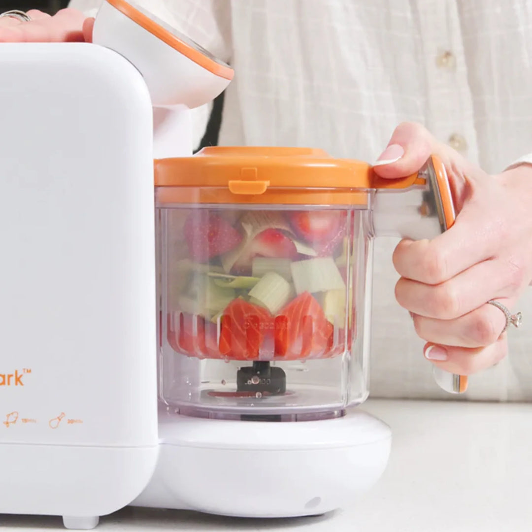 Parent using Quook 5-in-1 baby food maker to steam and blend fresh vegetables.
